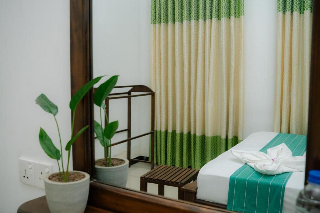 a bedroom with a bed and a mirror and plants at Kiula Resort in Hambantota