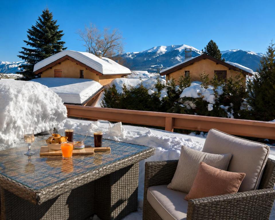a table and chairs on a patio in the snow at Résidence Campredon 3 étoiles - Terrasse 25m2 plein sud vue panoramique - Parking - Navette ski - wifi - Linge en option - Frais de ménage obligatoires in Font-Romeu
