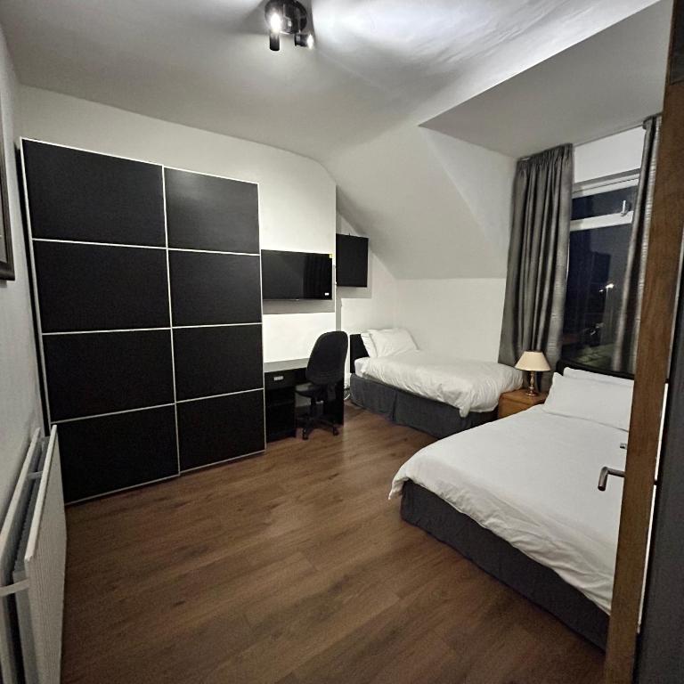 a hotel room with two beds and a desk at Haven Home 3 bedrooms near Sunderland City Centre Downstairs Shower with Toilet and Upstairs Bath with Toilet TV in each room in Sunderland