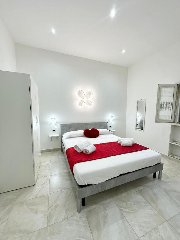 a white bedroom with a bed with a red blanket at Core Salentino Rooms in Campomarino
