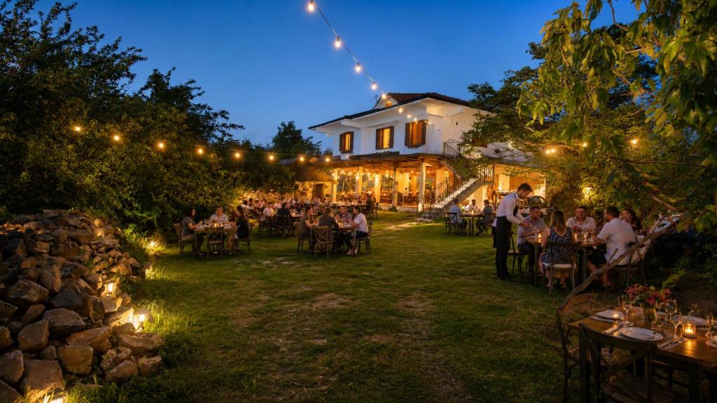 a group of people sitting at tables in a garden at night at Lugina e Qetesise in Librazhd