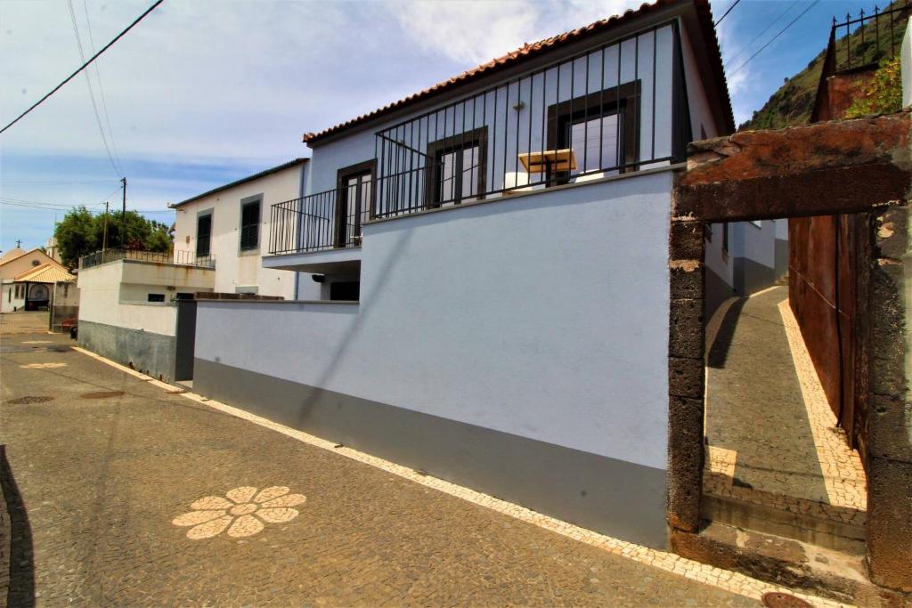 a white building with a balcony and a street at Jardim Mar Flats in Jardim do Mar