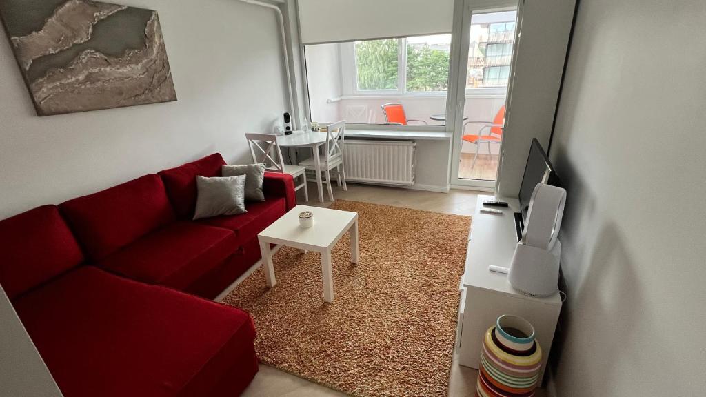 a living room with a red couch and a table at Apartamentai Vanagupės banga in Palanga
