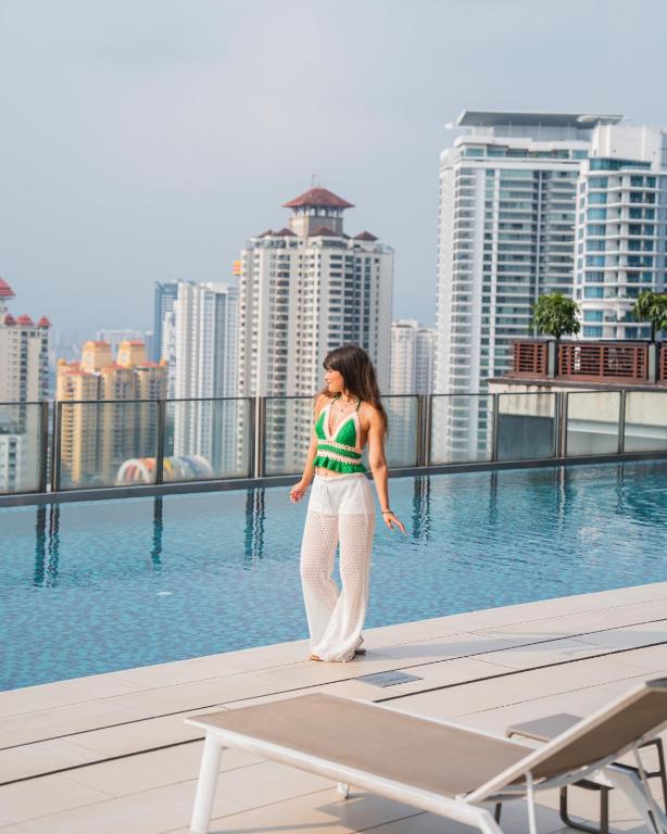 A rooftop pool terrace with loungers and a high-rise city view.