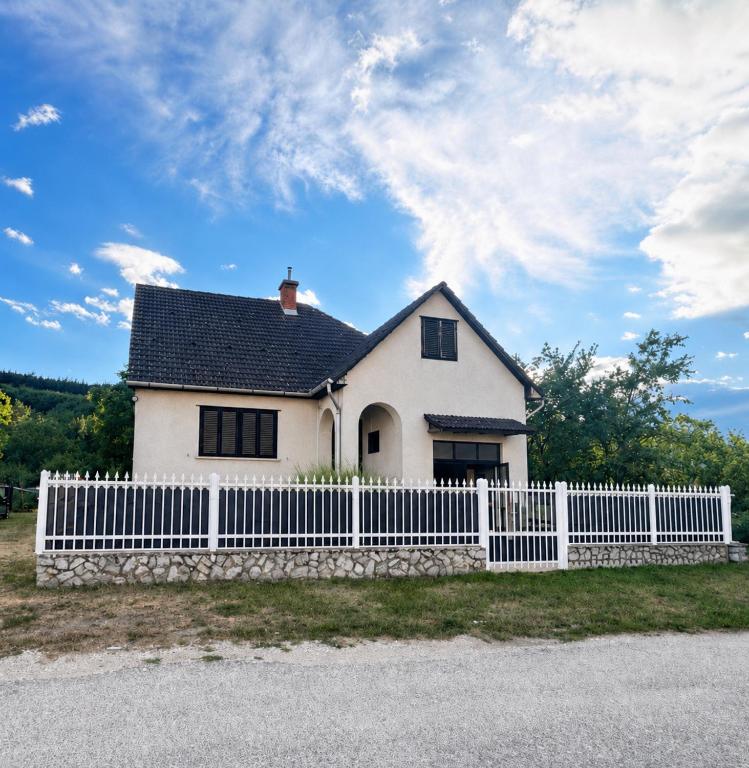 a white house with a white picket fence at Retro Land Bogács in Bogács