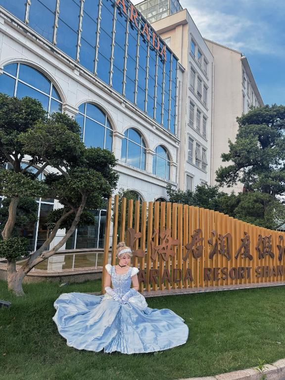 a girl in a blue dress sitting on the grass in front of a building at NARADA Resort Shanghai Hotel Disney Store in Shanghai
