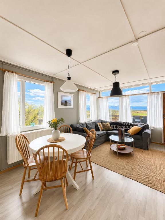a living room with a table and chairs and a couch at Hestaland Riverside Cottage in Staðarhús