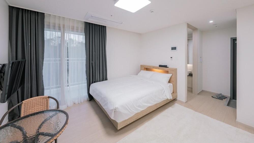 a white bedroom with a bed and a window at E7 YangYang Jukdo - Yangyang Stay Dongsan in Saetchak