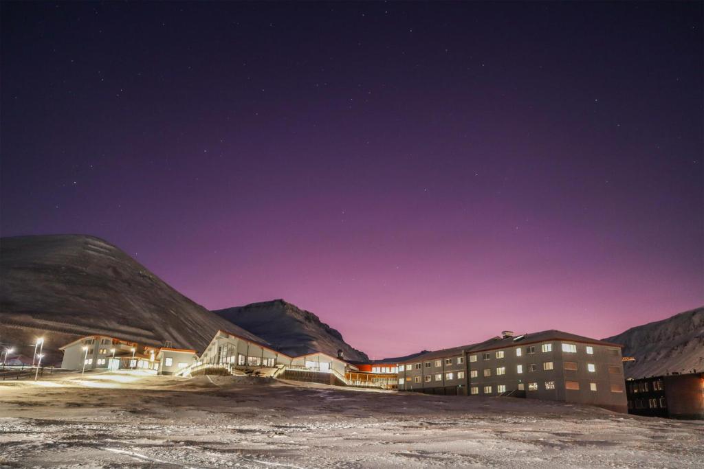 a hotel at night with mountains in the background at Radisson Blu Polar Hotel, Spitsbergen in Longyearbyen
