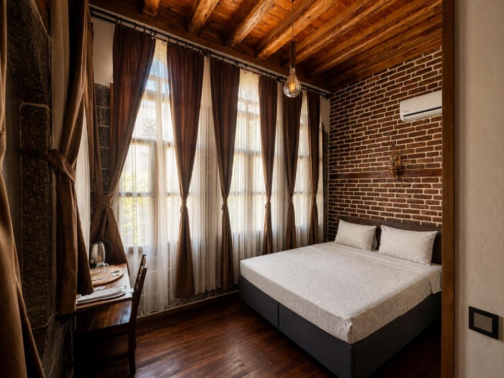 a bedroom with a bed and a brick wall at Taş Avlu Konaklama Tesisi in Diyarbakır