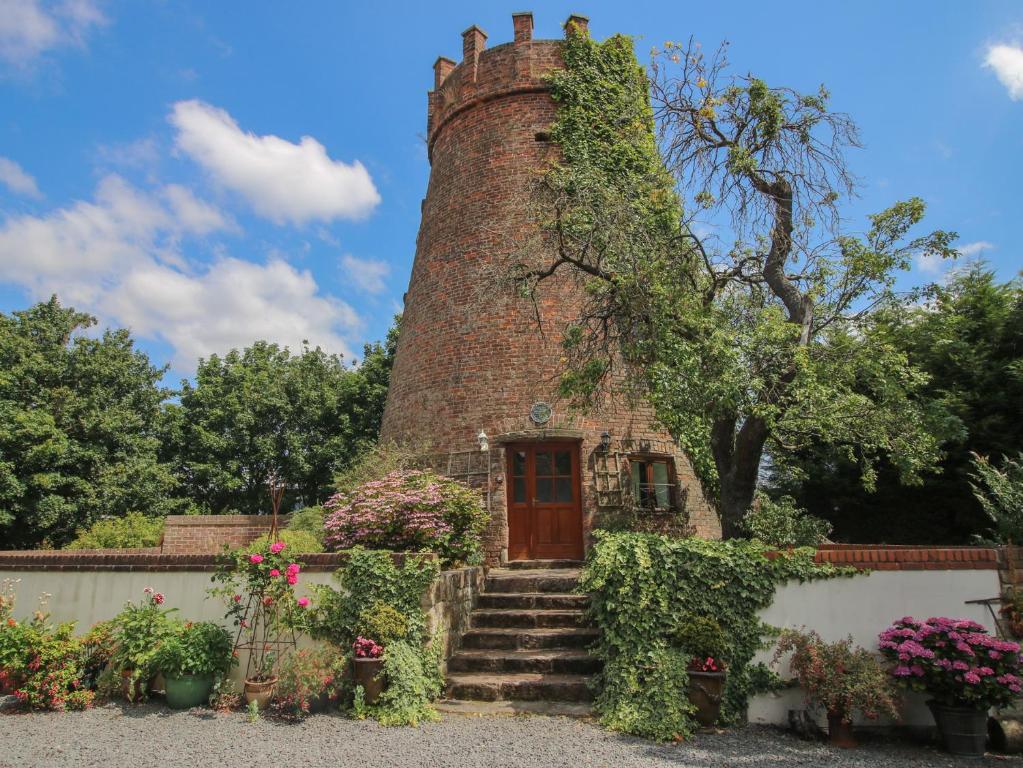 a house with a brick tower with stairs and flowers at Hadley Park Windmill in Telford
