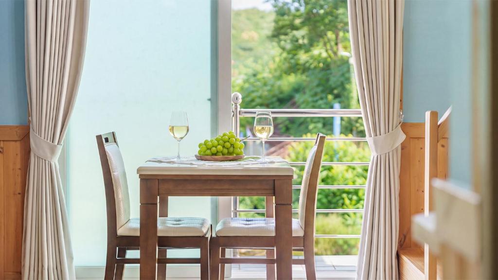 a table with two glasses of wine and a bowl of fruit at Samcheok Healingcamp Pension in Samcheok