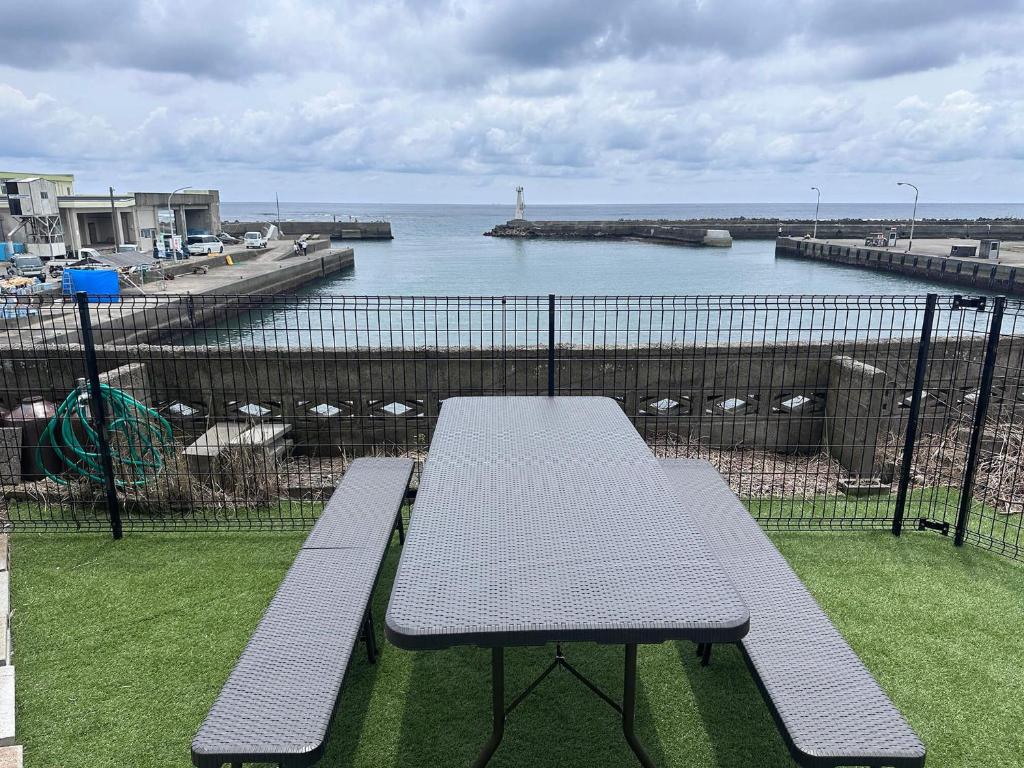 a picnic table and benches on a balcony overlooking the water at 勝浦の家 in Katsuura