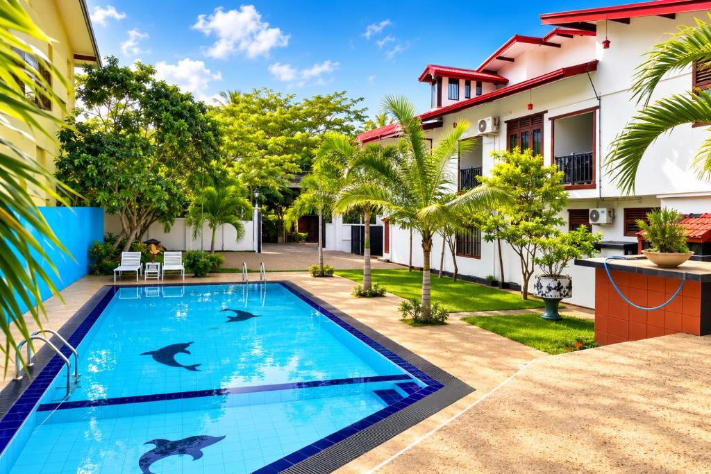 a swimming pool in the backyard of a house with dolphins in the water at Glory Rajarata Lakeside Resort in Anuradhapura