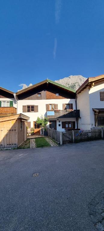a white building with a fence next to a street at Ferienhaus Klotz mit Kinderzimmer und Spielsachen in Mittenwald