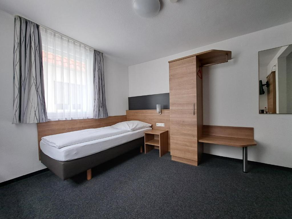 a bedroom with a bed and a desk and a window at Hotel zur Post in Weilheim an der Teck