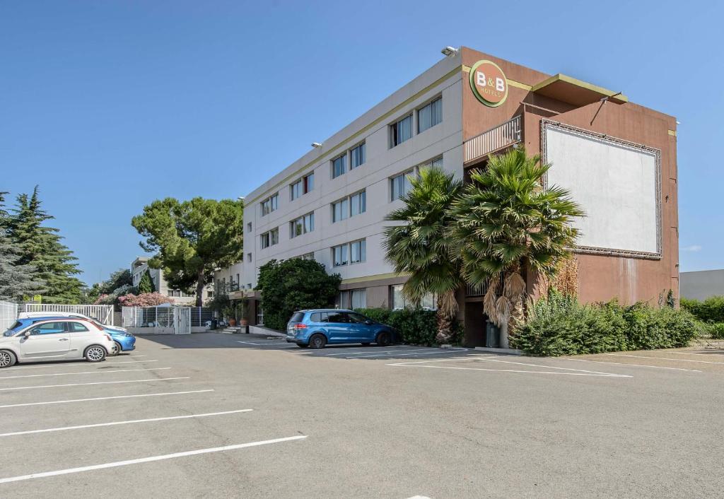 a large building with cars parked in a parking lot at B&B HOTEL Nîmes Ville Active 3 étoiles in Nîmes