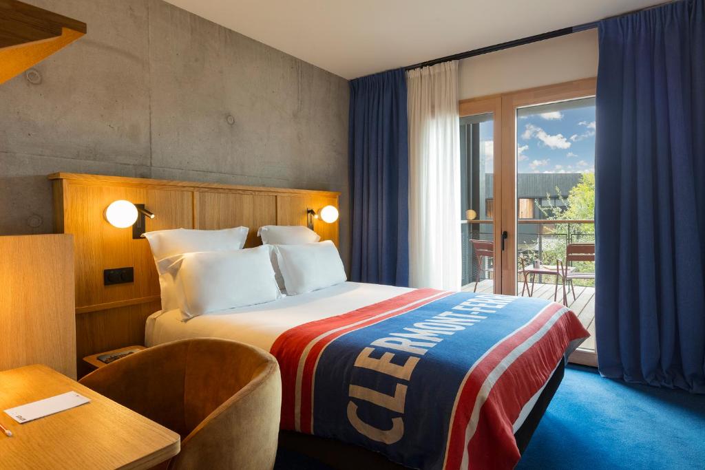 a hotel room with a bed and a desk and a window at Grand Mess Clermont-Ferrand in Clermont-Ferrand