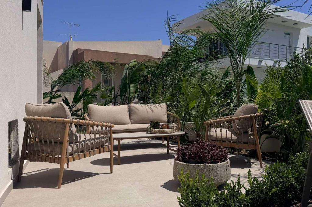 two chairs and a table on a patio with plants at Mirena Exclusive Apartments in Afantou