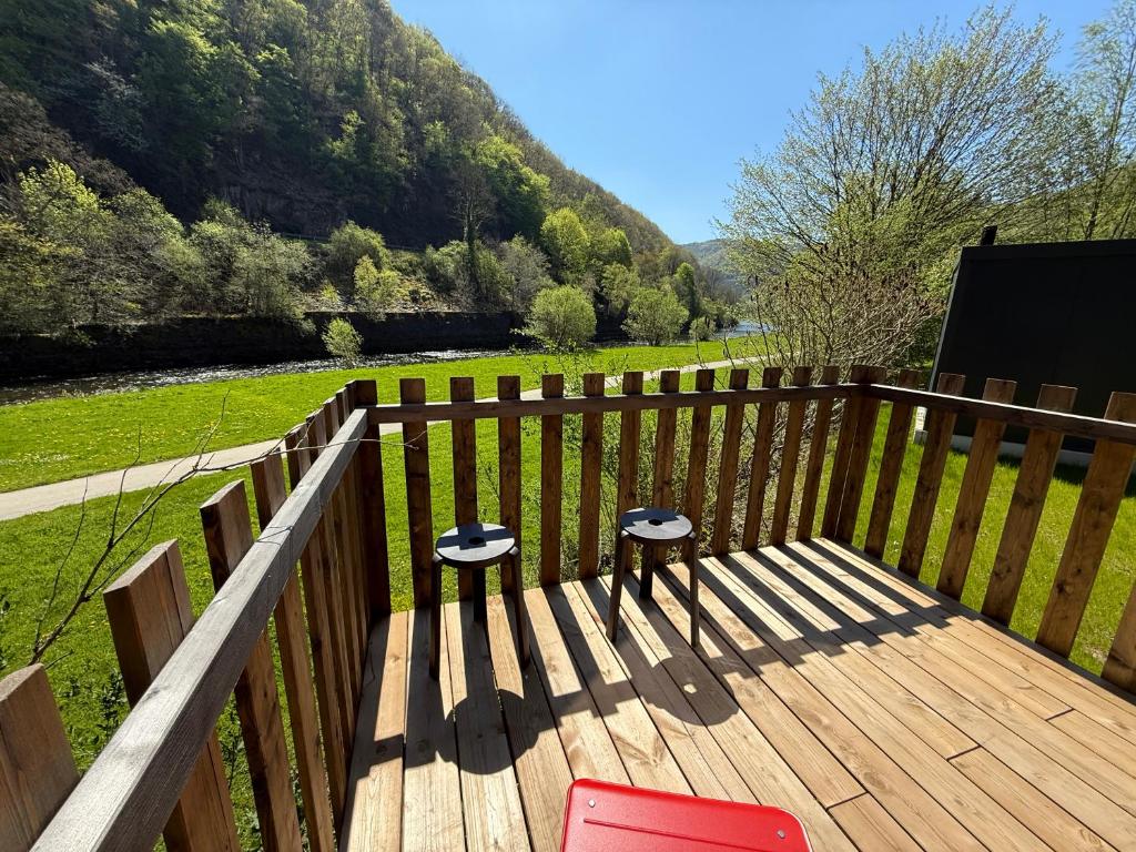 a wooden deck with two chairs and a view of a field at Camping Pier10 in Bourscheid