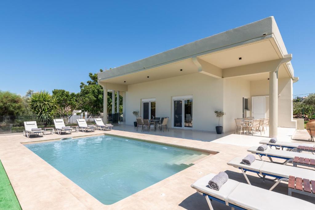 a swimming pool with lounge chairs and a house at Cielo Hillside Villa in Ialysos