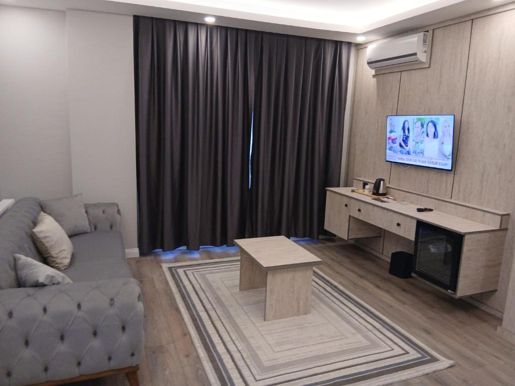 a living room with a couch and a table and a television at Sunset Hill Hotel in Büyükçekmece