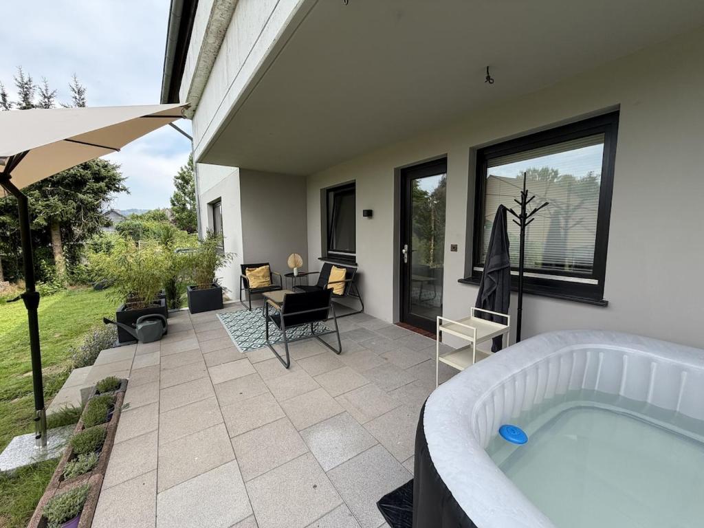 a patio with a hot tub and a table and chairs at Gemütliche Ferienwohnung direkt am Waldrand in Dörentrup