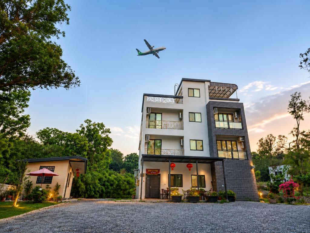 an airplane flies over a house with a building at Kinmen Life With Bird Homestay- Near Kinmen Airport in Jinhu