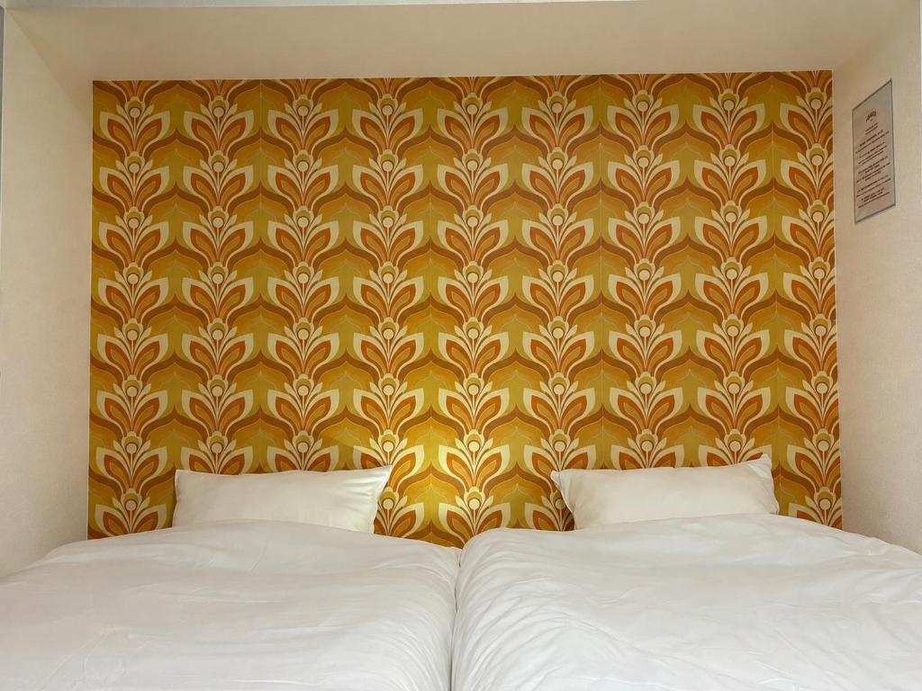 a bedroom with two beds and a yellow wall at Haraya in Nakatsugawa