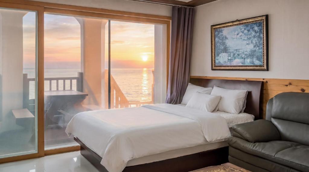 a bedroom with a bed and a couch and a window at Youngduk Sea & Spa Pension in Yŏngdŏk