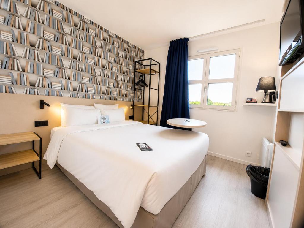 a bedroom with a large white bed and a window at Kyriad Hôtel La Fleche in La Flèche