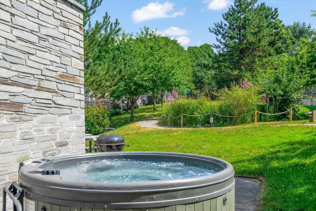 a hot tub in a yard next to a stone building at House 8 in Looe