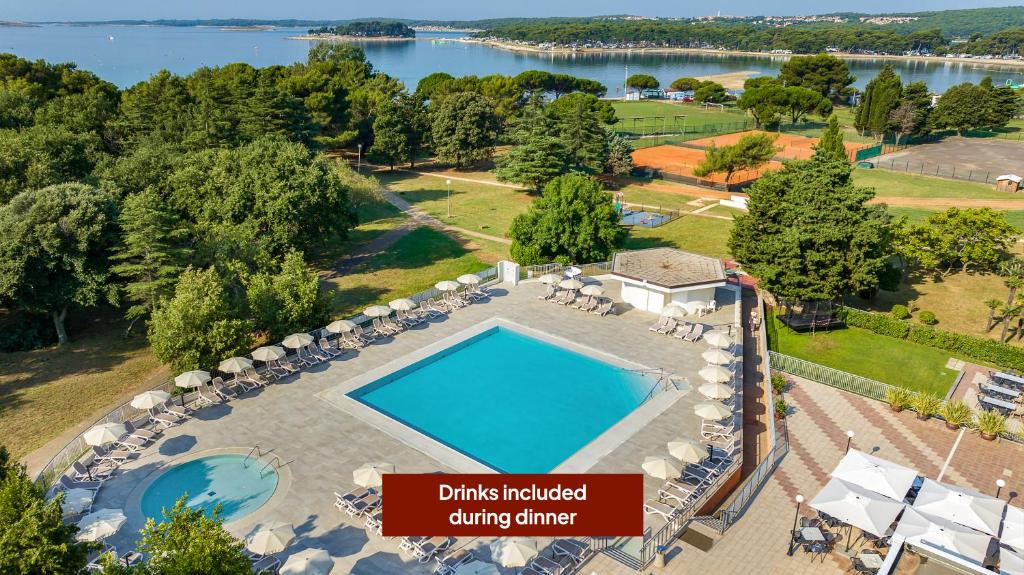 an aerial view of a swimming pool with chairs and a lake at Arena Hotel Holiday in Medulin