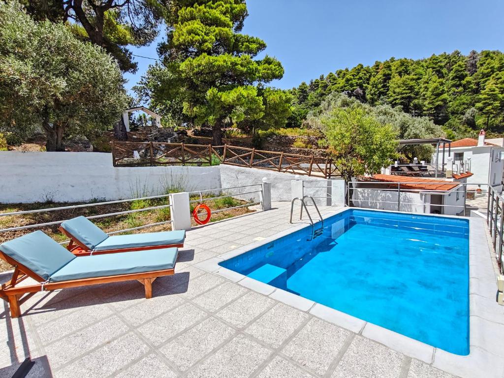 a swimming pool with two lounge chairs next to a swimming pool at The Mountain Majesty in Skopelos Town