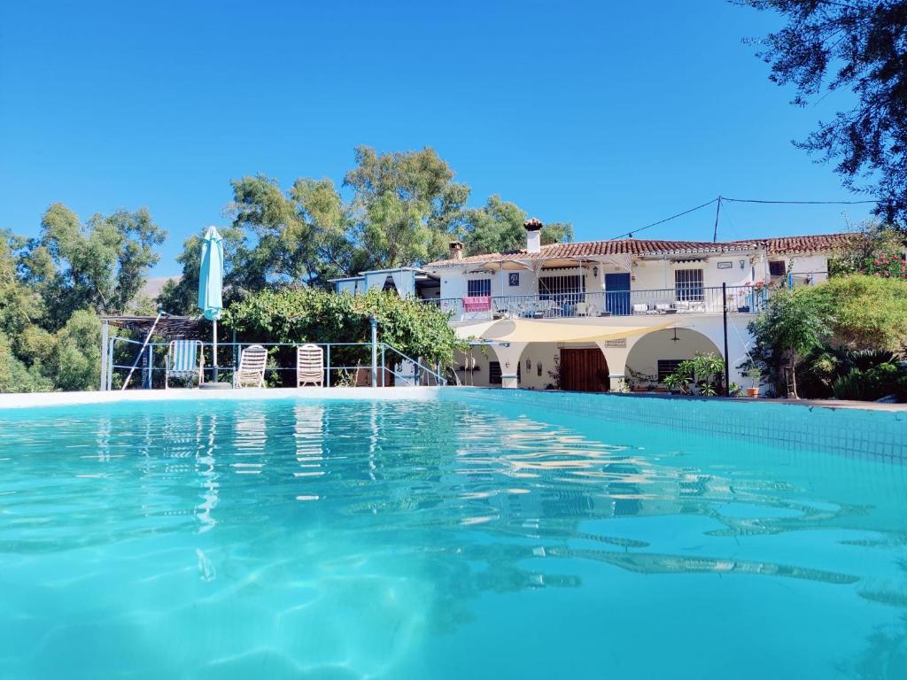 a swimming pool in front of a house at Cortijo el Puente in Viñuela