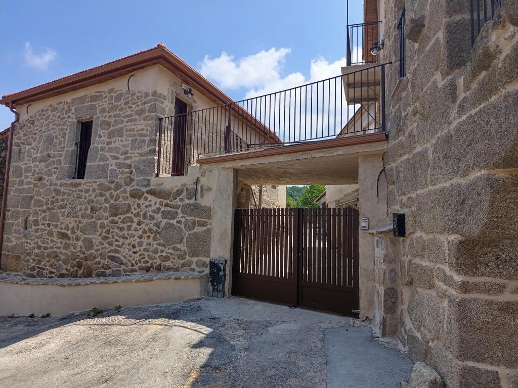 a stone house with a wooden gate and a balcony at As Casiñas da Mina in Fechas