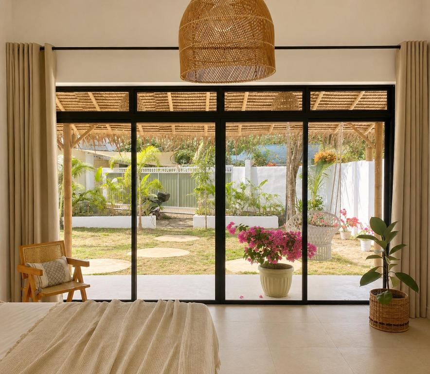a bedroom with a large sliding glass door to a garden at CASA BUKO Tropical Homes El Nido in El Nido