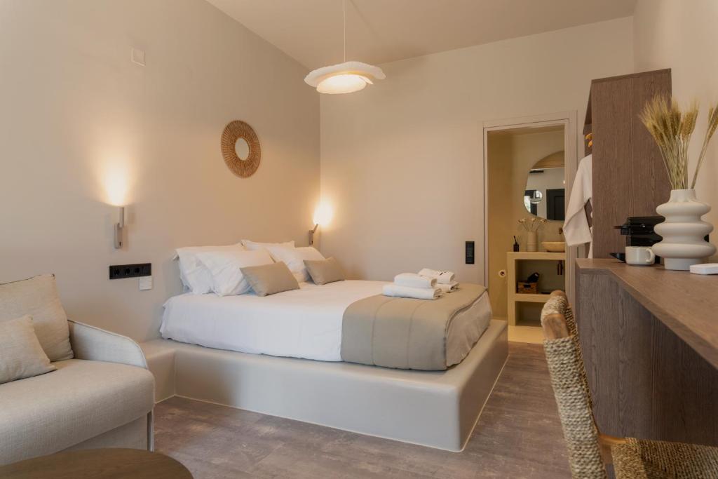 a white bedroom with a bed and a couch at Ichos Boutique Apartments in Volissos