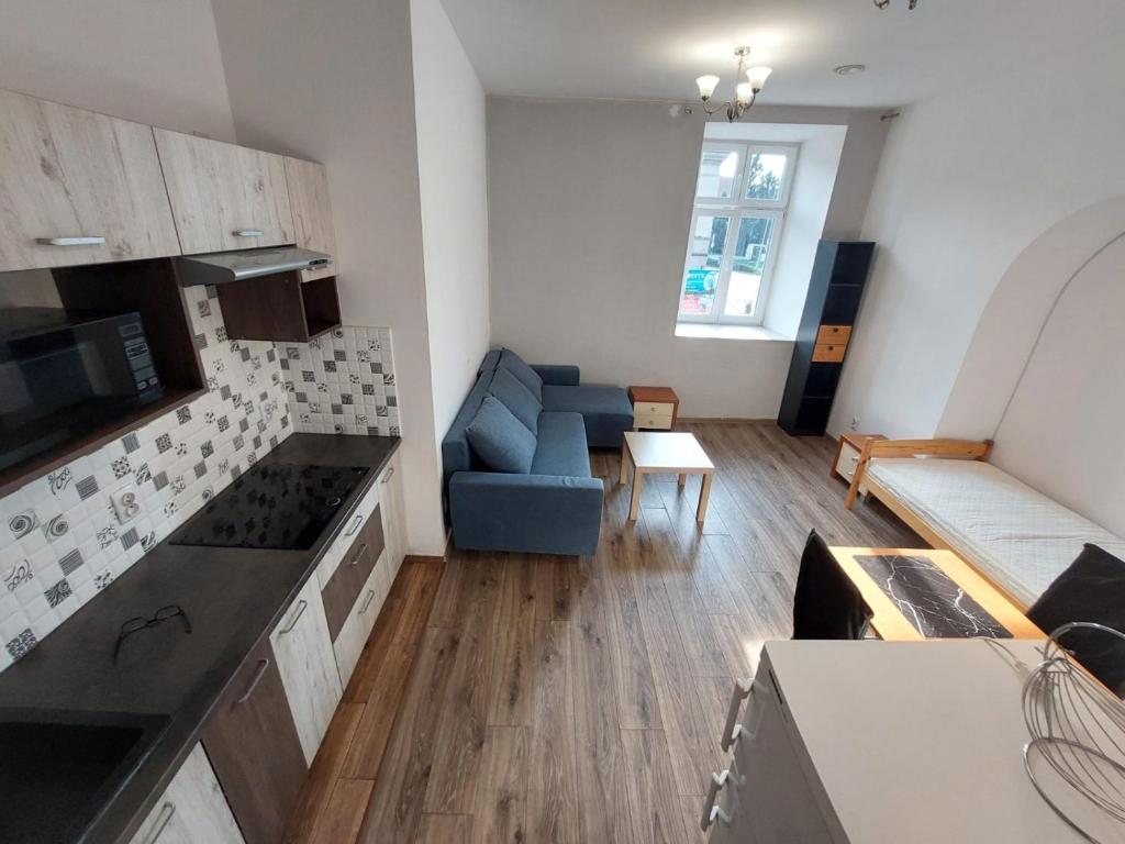 a kitchen and a living room with a blue couch at Apartamenty Floris Bochnia in Bochnia