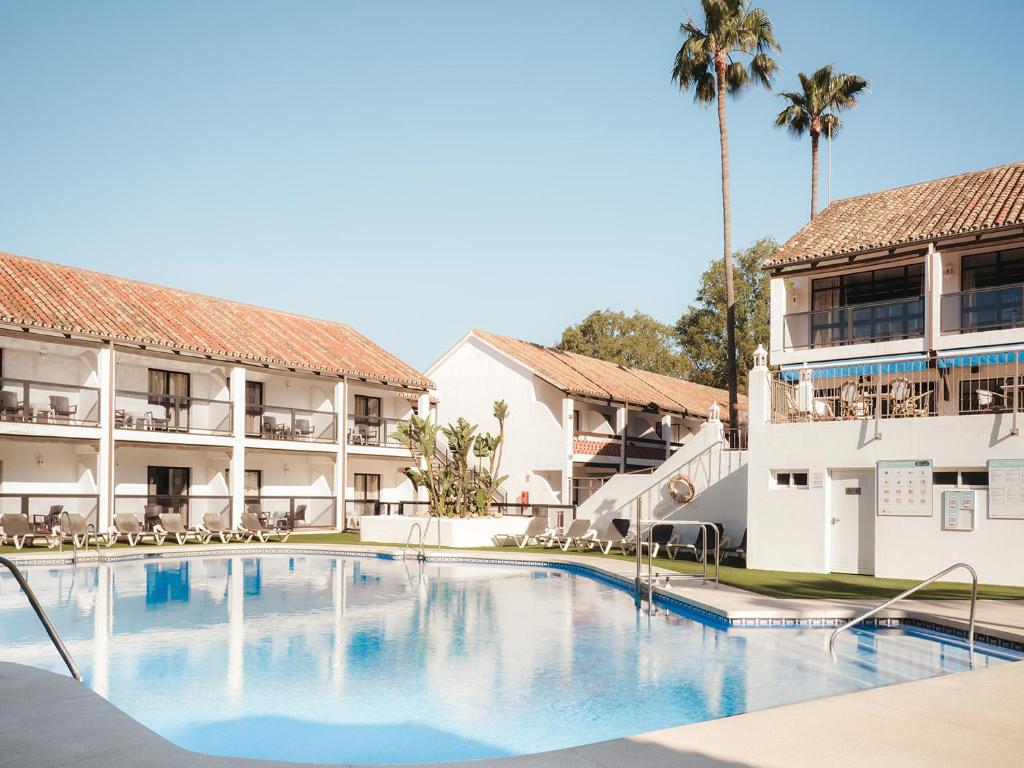 a swimming pool in front of a hotel with palm trees at Ona Diana Park in Estepona