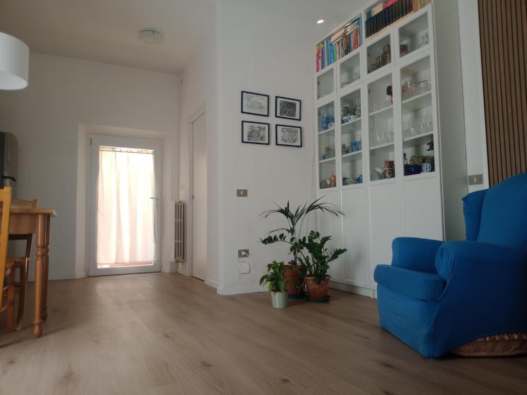a living room with a blue chair and a window at Appartamento con giardino e posto auto privato in Follonica