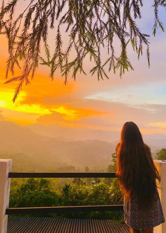 a woman standing on a balcony looking at the sunset at Roo Heaven Villas in Haputale