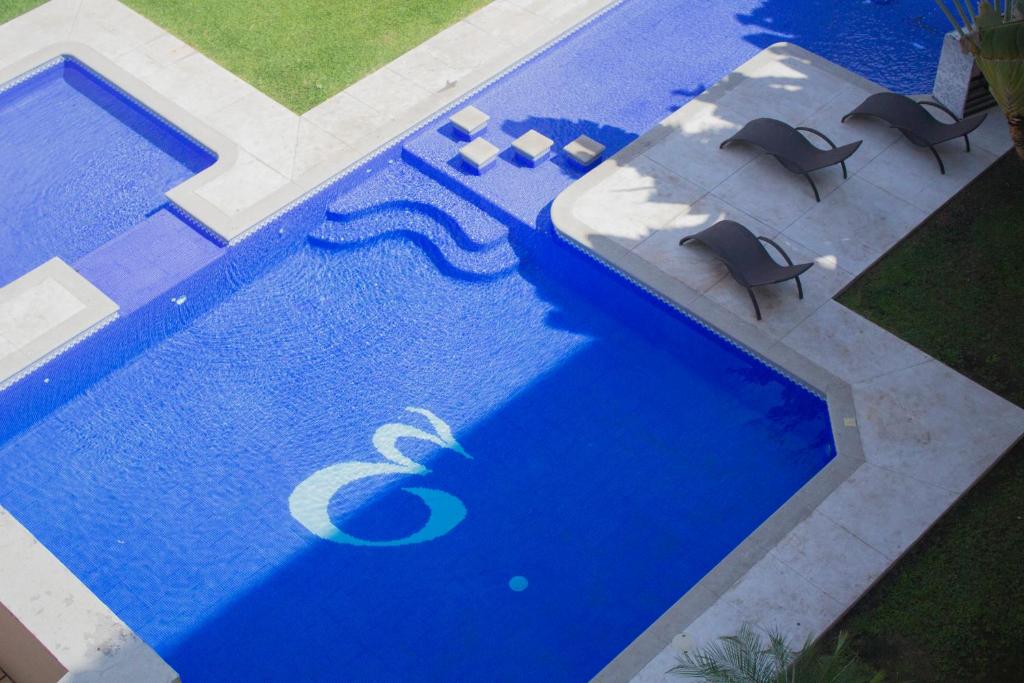 an overhead view of a blue swimming pool with two chairs at EH Ejecutivo Urban in Tepic