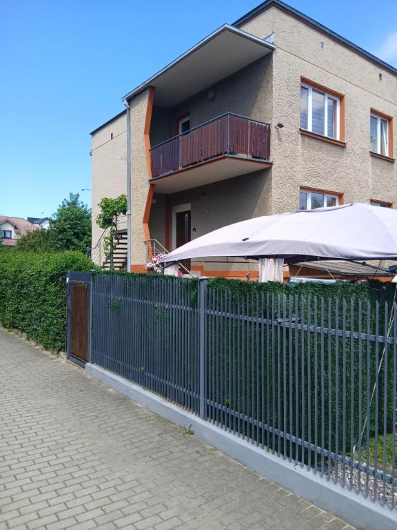 a fence with an umbrella next to a house at Noclegi Grota in Jasło