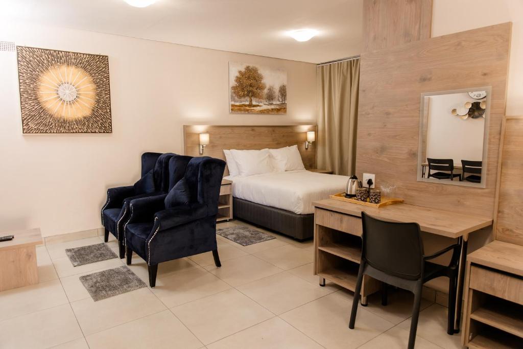 a hotel room with a bed and a desk and chairs at Wilkoppies Self Catering in Klerksdorp