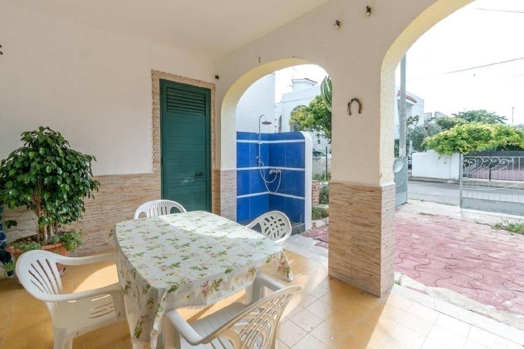 a table and chairs on a patio with a blue door at Villino Carolina in Porto Cesareo