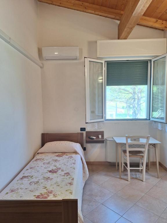 a bedroom with a bed and a table and a window at Locanda dei Sapori in Marozzo