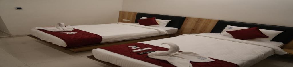 two beds in a hotel room with towels on them at Hotel Laasya Grand in Vijayawāda