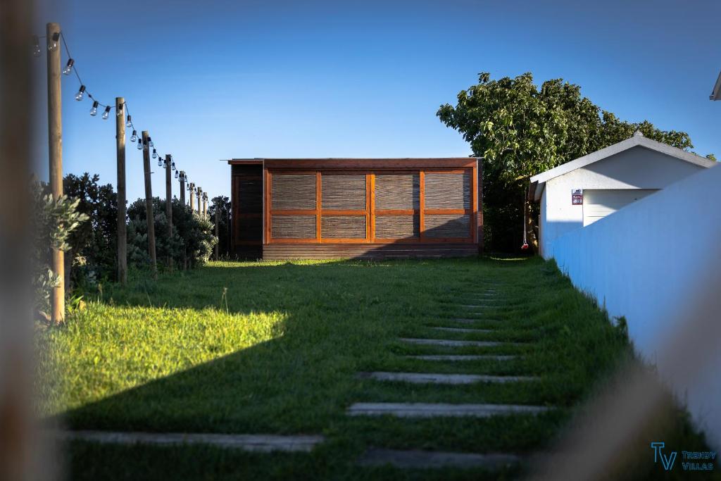 a house with wooden doors and a grass yard at Trendy Villas Hostel in Vila Chã