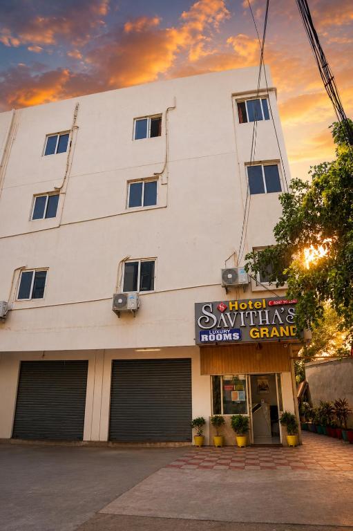 a white building with a sign in front of it at Hotel Savithas Grand in Vijayawāda